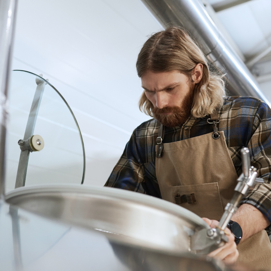 A man looking into a brewery vat.