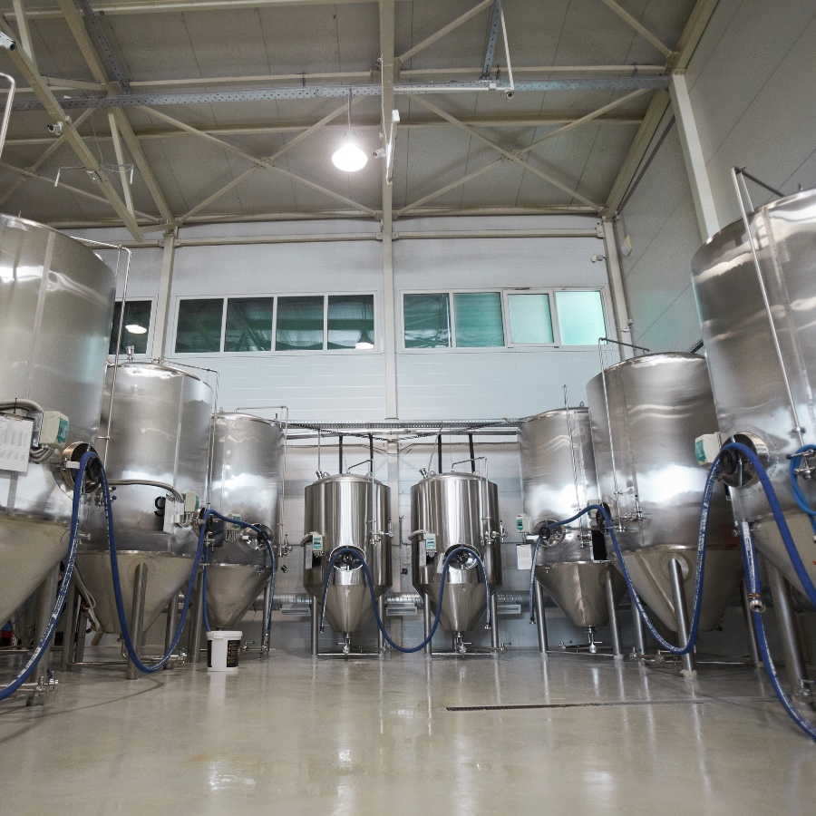 Large warehouse space with multiple brewery vats in stainless steel.
